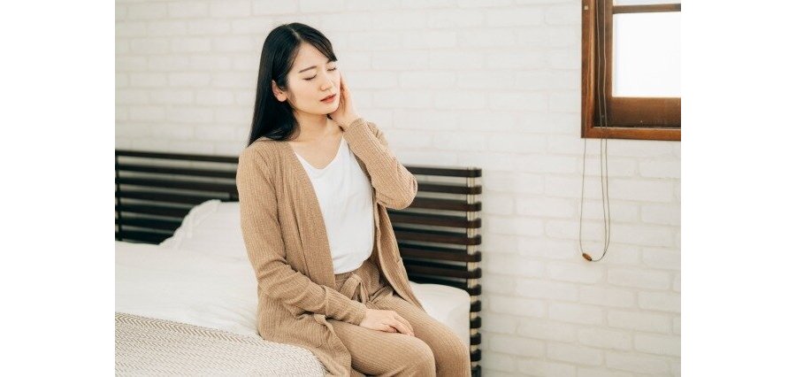 ベッドで頬を押さえている女性